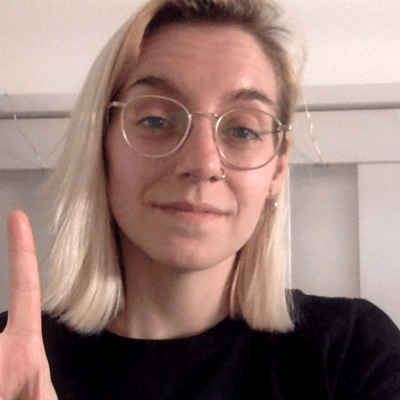 Head and shoulders shot of a smiling Robyn Elton wearing glasses and doing the peace sign with her right hand